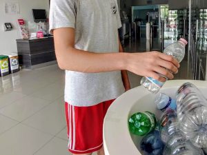 un ragazzo conferisce una bottiglietta di plastica nell'apposito contenitore nella reception del Q-bo Wellness durante il concorso a premi di ottobre